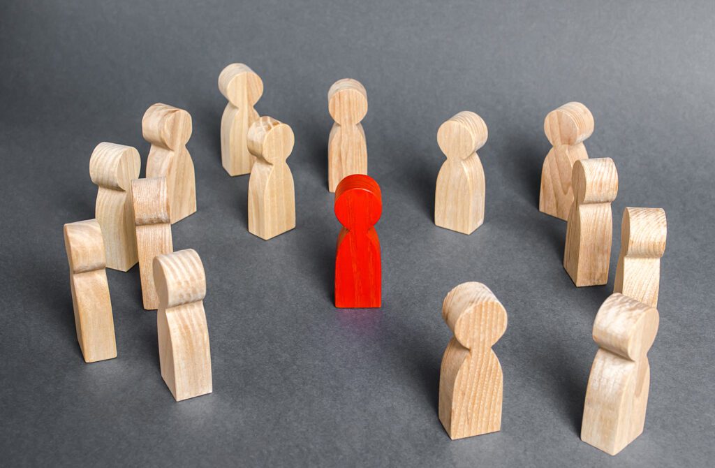 Red painted wooden human figure surrounded by a group of people.